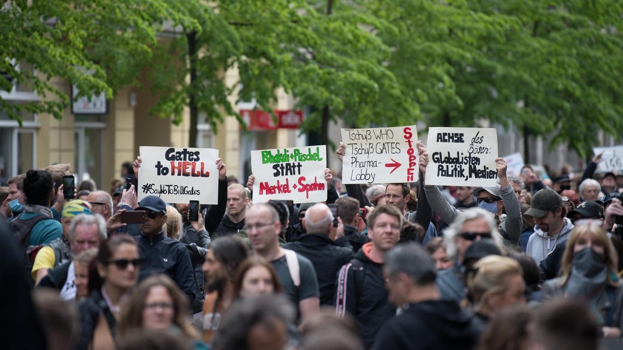 Demonstranten halten bei der Kungebung in Berlin Schilder hoch, auf denen sie unter anderem Bill Gates und die WHO angreifen.