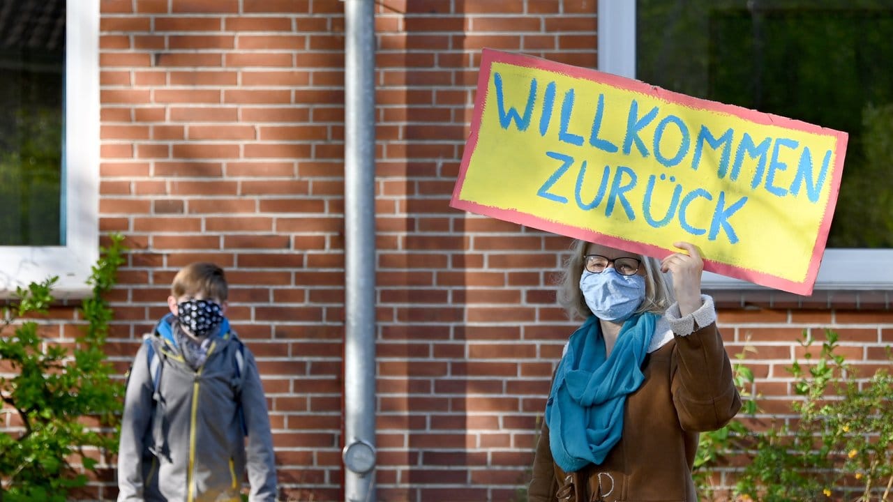 Eine Lehrerin in Schleswig-Holstein begrüßt ihre Schüler mit einem "Willkommen zurück"-Schild.
