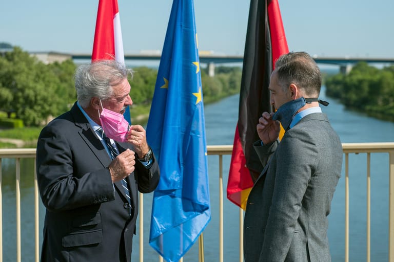 Der Luxemburger Außenminister Jean Asselborn und Bundesaußenminister Heiko Maas (SPD) nehmen bei ihrem Treffen auf der Brücke über die Mosel ihren Mundschutz ab: Dass Maas nun wieder fliegt, sorgte für Kritik.