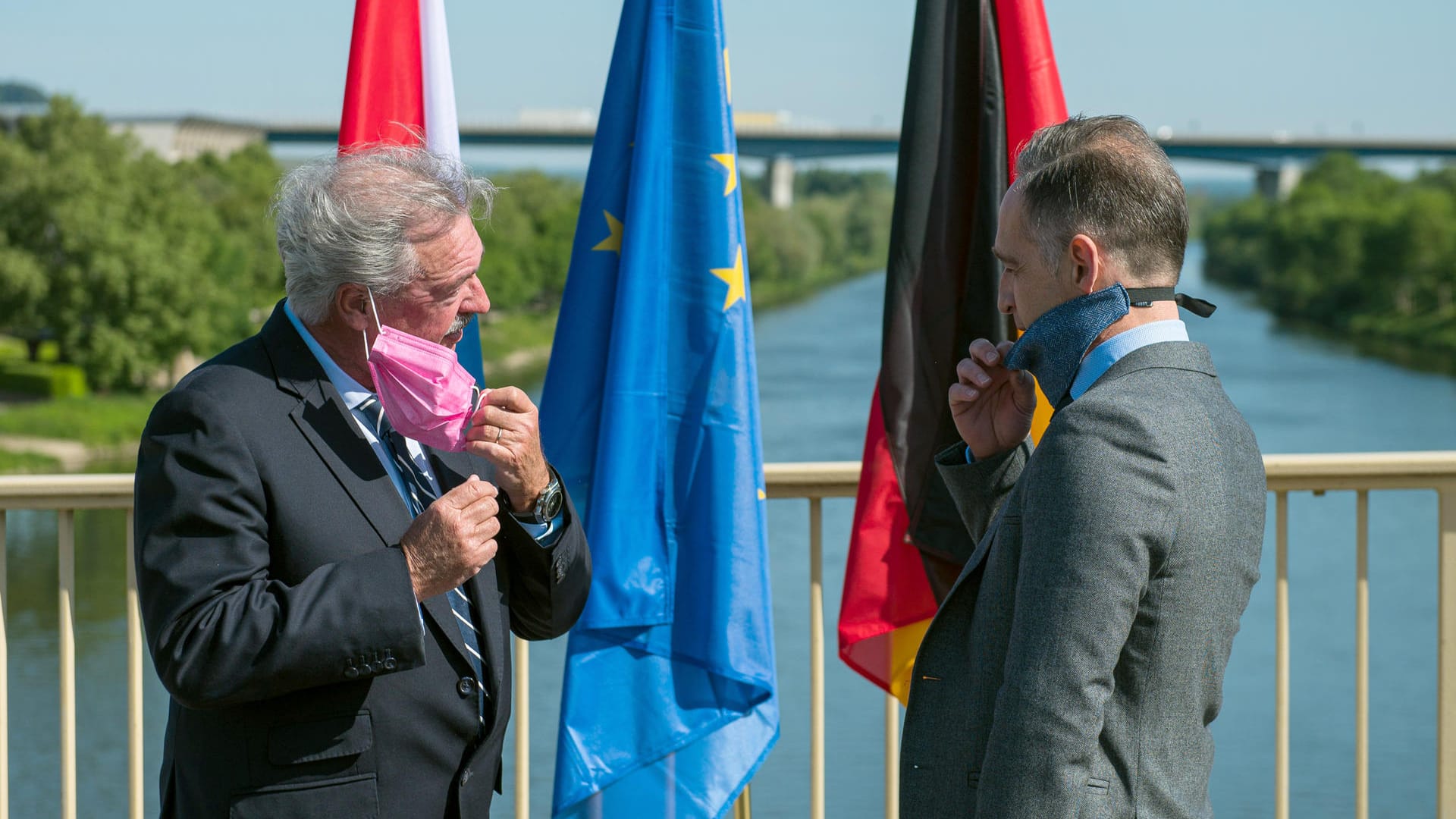 Der Luxemburger Außenminister Jean Asselborn und Bundesaußenminister Heiko Maas (SPD) nehmen bei ihrem Treffen auf der Brücke über die Mosel ihren Mundschutz ab: Dass Maas nun wieder fliegt, sorgte für Kritik.