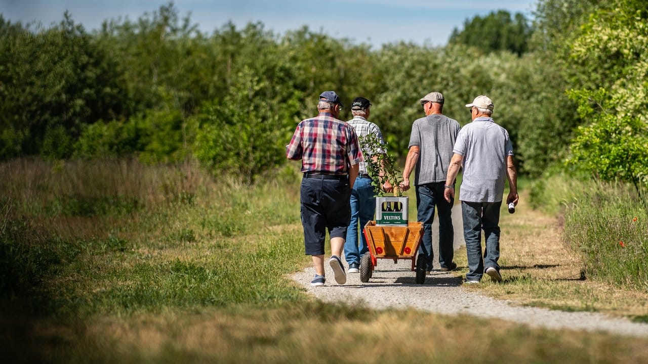 Traditionalisten: Vier Männer gehen am Vatertag mit einem Bollerwagen, auf dem zwei Kisten Bier stehen, an der Ems in Warendorf entlang.