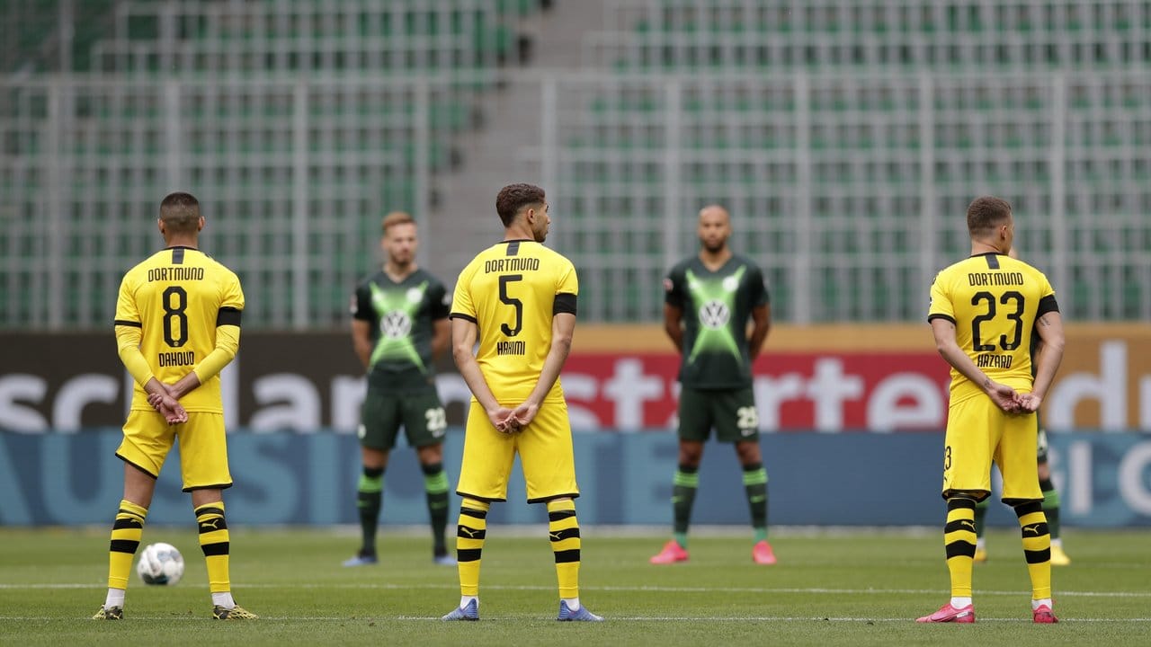 Die Spieler beider Mannschaften (Dortmund gelbes Trikot) gedenken mit einer Schweigeminute den Opfern der Corona-Pandemie.