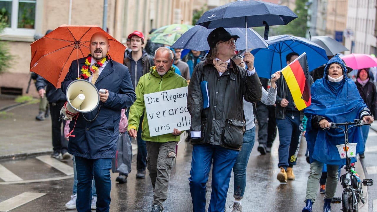 Angeführt von dem parteilosen Landtagsabgeordneten Heinrich Fiechtner (mit Schirm) und dem AfD-Landtagsabgeordneten Stefan Räpple (l) nehmen Menschen an einer Demonstration in Stuttgart teil.