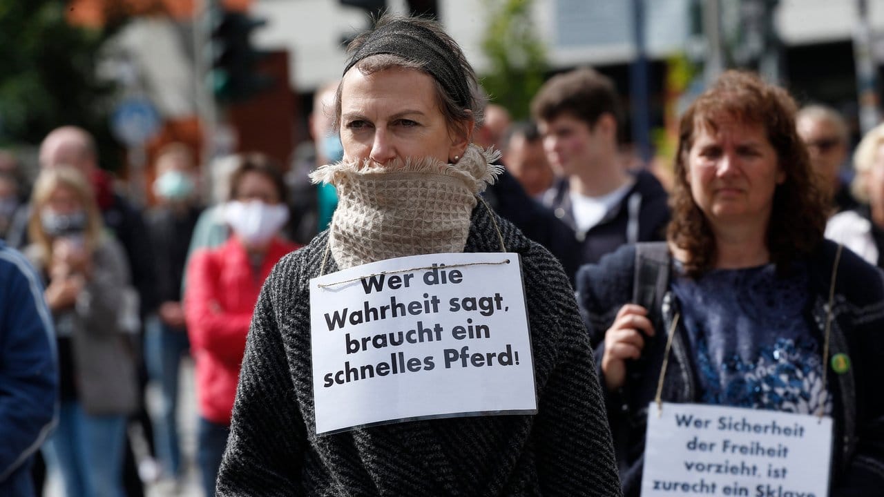 Demonstrantinnen in Hamburg haben sich Schilder umgehängt.