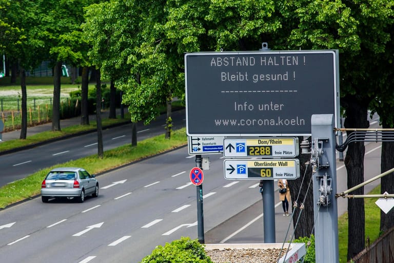 Eine Anzeigetafel mahnt am Rheinufer in Köln zum Abstandhalten.