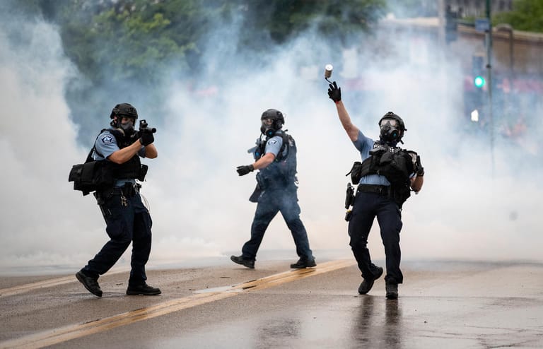 Die Polizei wirft Tränengasgranaten in Richtung der Demonstranten.