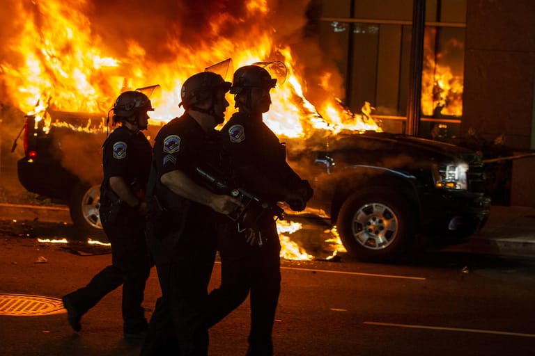 Washington, D.C. ist ein zentraler Ort der Proteste: Polizisten laufen an brennenden Autos vorbei.