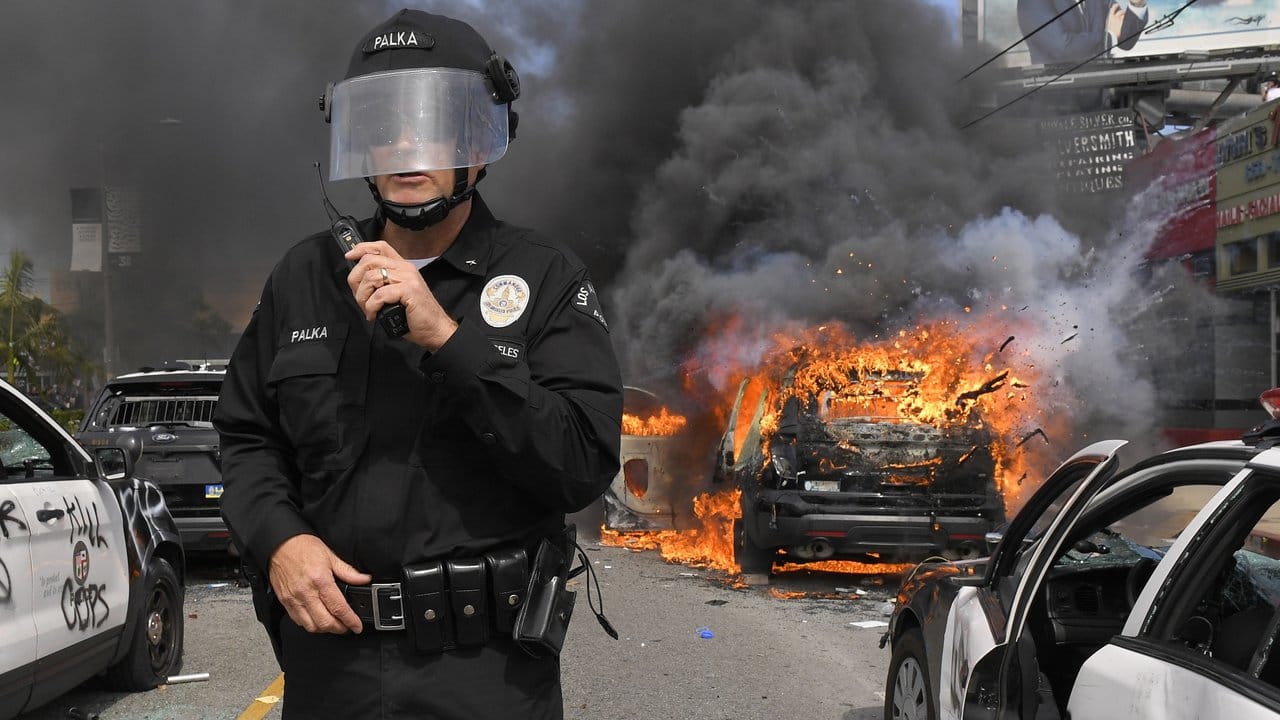 Cory Palka, Kommandeur des Los Angeles Police Department, während eines Protests zwischen mehreren zerstörten, in Flammen stehenden Polizeiautos.