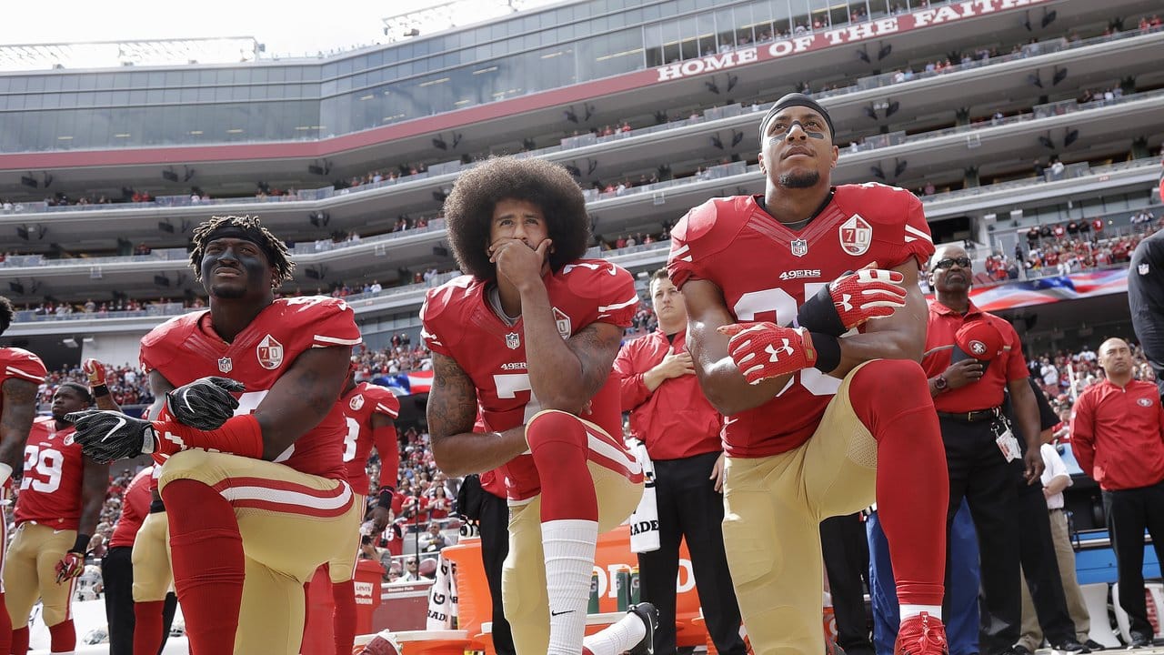 Gegen Rassismus und Polizeigewalt: Colin Kaepernick (M) kniet mit Teamkollegen während der Nationalhymne vor einem NFL-Spiel. Gegen Rassismus und Polizeigewalt: Colin Kaepernick (M) kniet mit Teamkollegen während der Nationalhymne vor einem NFL-Spiel.