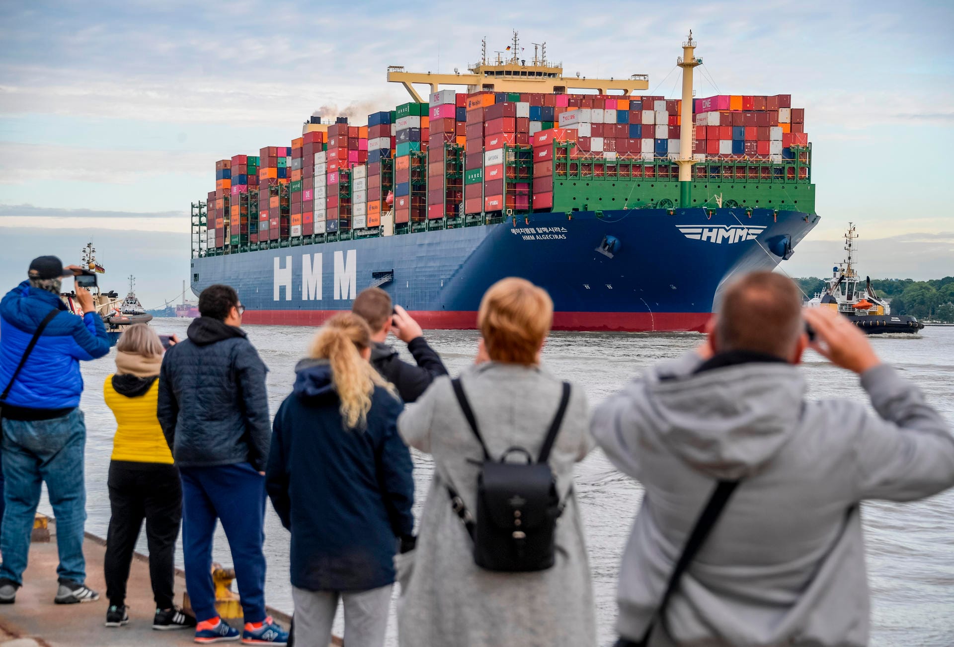 Menschen stehen mit Kameras am Elbufer: Das weltgrößte Containerschiff "HMM Algeciras" hat viele Schaulustige angezogen.