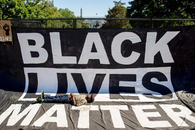 Ein Mann liegt auf einem großen Banner mit der Aufschrift "Black Lives Matter".