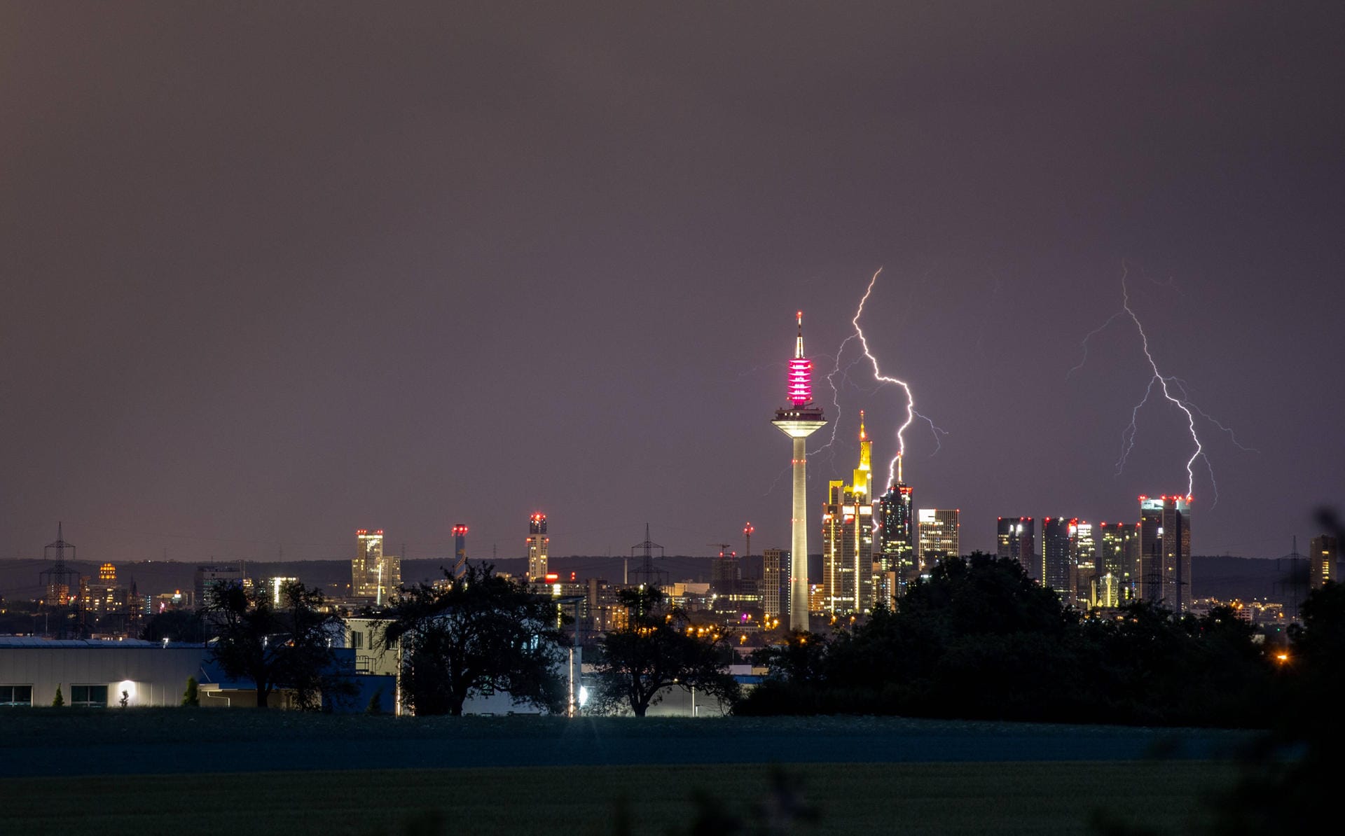 Hessen: Blitze eines Gewitters sind am späten Abend am Himmel über der Frankfurter Skyline zu sehen.