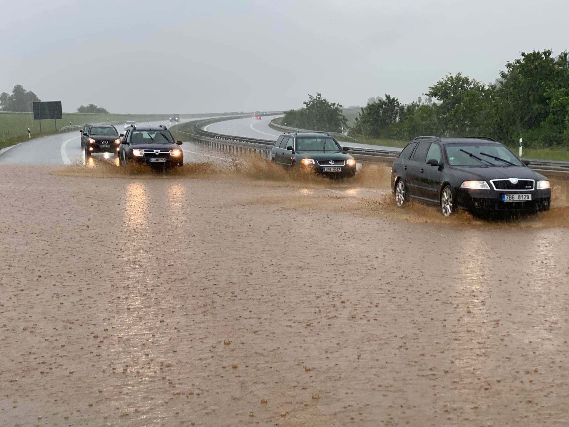 Bayern, Wieselrieth: Autos fahren bei starkem Regen auf der zum Teil unter Wasser stehenden Autobahn 6.
