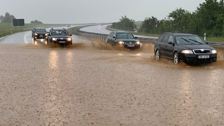 Bayern, Wieselrieth: Autos fahren bei starkem Regen auf der zum Teil unter Wasser stehenden Autobahn 6.