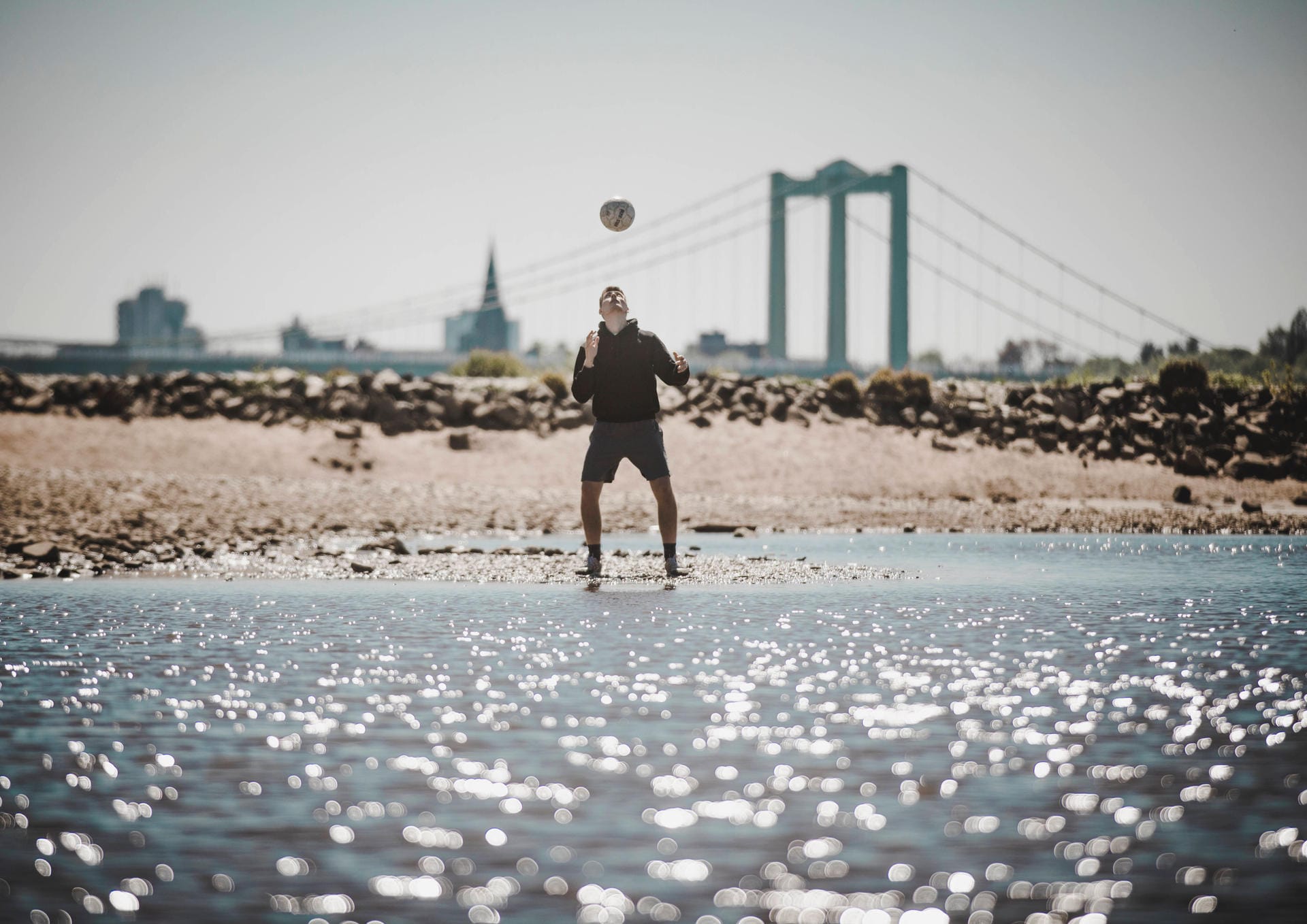 Sport am Rhein: Ein junger Mann vertreibt sich die Zeit mit Fussball. Der Rhein ist bei den Kölnern als Ort zum Sporttreiben beliebt.