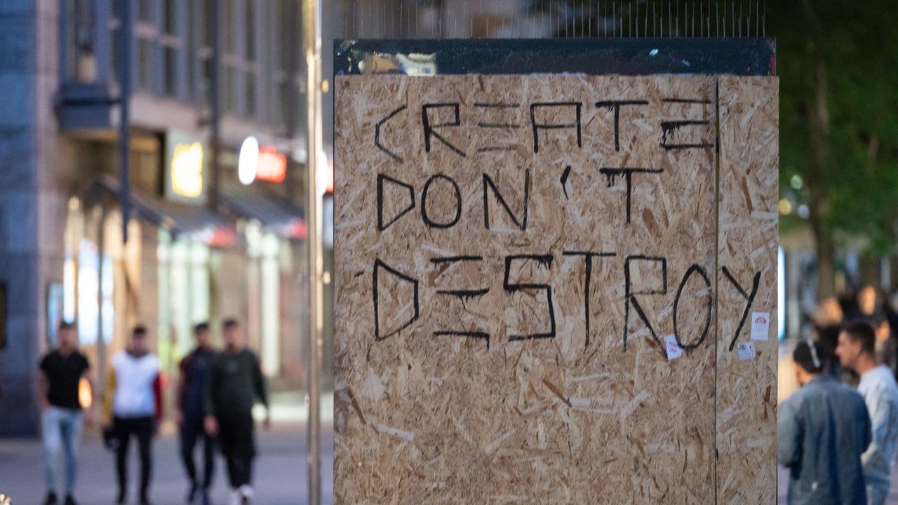 Die Worte "Create don't Destroy" (Erschaffe statt zu zerstören) stehen auf Holzplatten, mit denen in Stuttgart die beschädigte Scheibe einer Werbetafel abgedeckt worden ist.