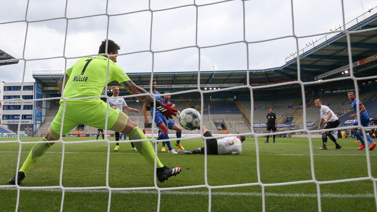 Bielefelds Fabian Klos (am Boden) hat den Treffer zum 1:0 gegen Heidenheims Torwart Kevin Müller (l) erzielt.