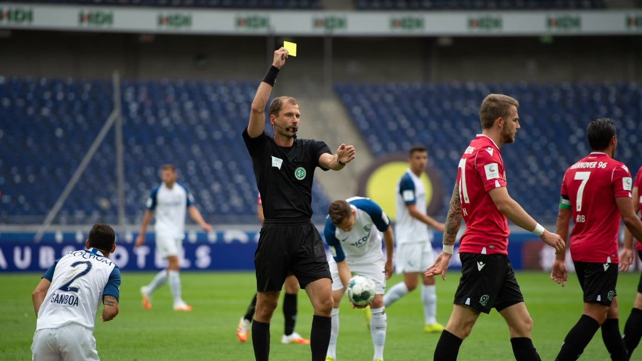 Schiedsrichter Rene Rohde zeigt Hannovers Jannes Horn (r) für ein Foul die Gelbe Karte.