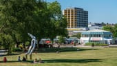 Besucher sitzen auf der Kranichwiese im Grugapark: Dort steht die Skulptur "Orion" von Brigitte Matschinsky-Denninghoff und Martin Maschinsky (1987).