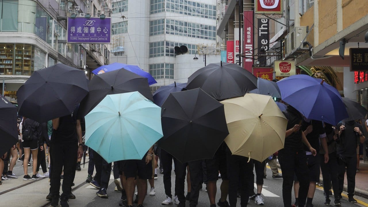 Demonstranten bilden mit Regenschirmen ein Schutzschild.
