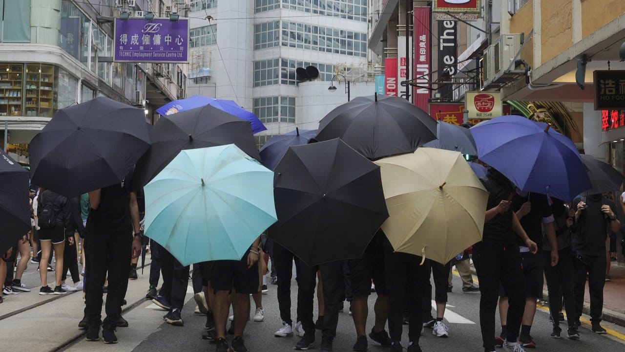 Demonstranten bilden ein Schutzschild aus Regenschirmen.