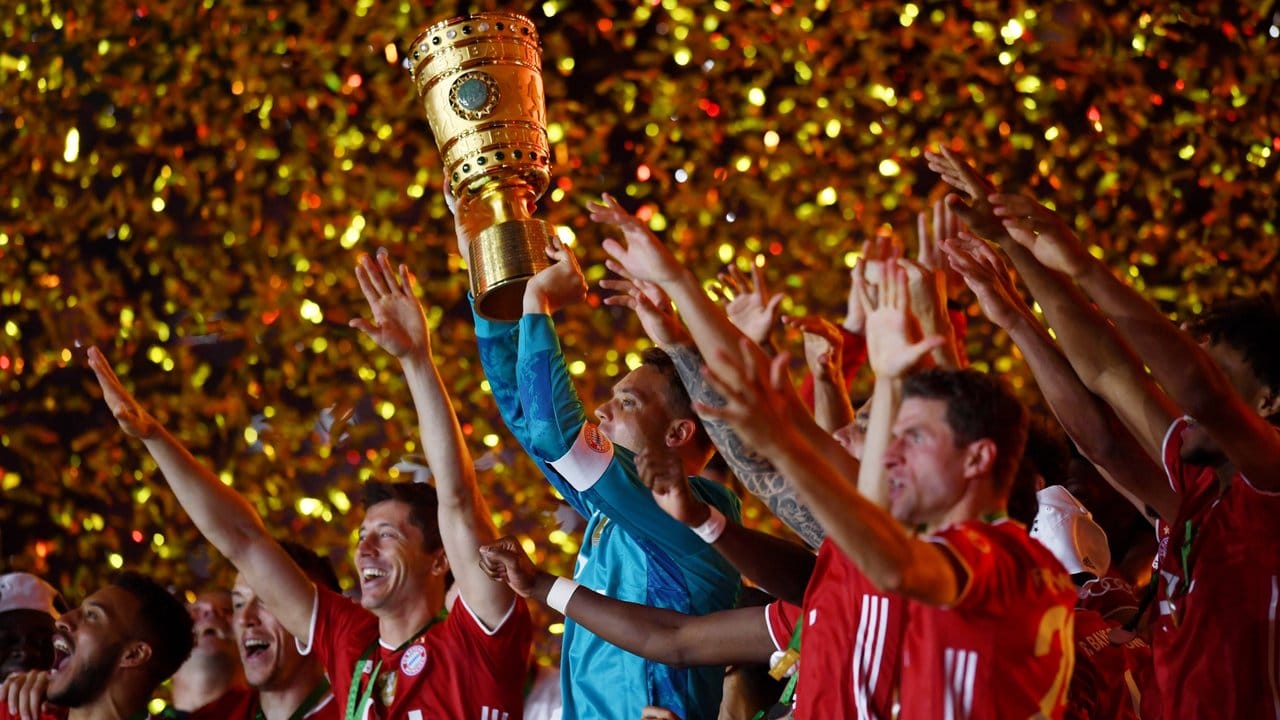 Münchens Torhüter Manuel Neuer hält die Trophäe jubelt mit dem DFB-Pokal.