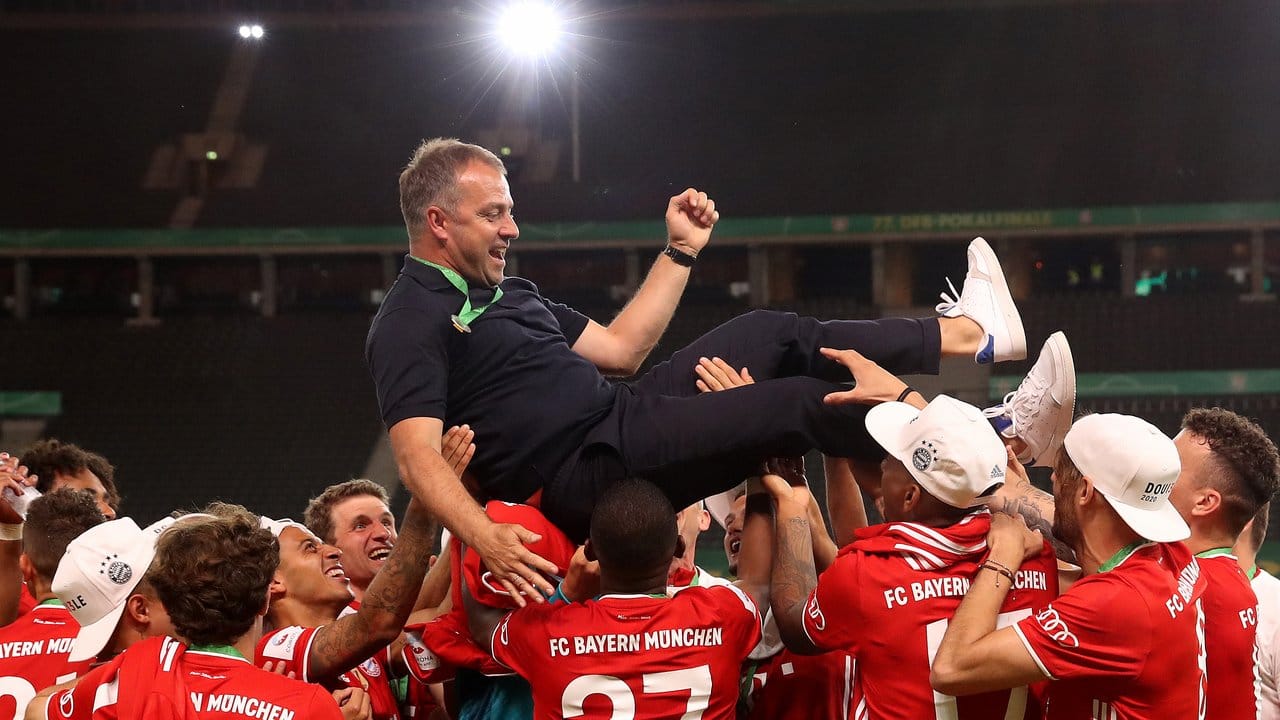 Münchens Trainer Hansi Flick wird von seinen Spielern in die Luft geworfen. Münchens Trainer Hansi Flick wird von seinen Spielern in die Luft geworfen.