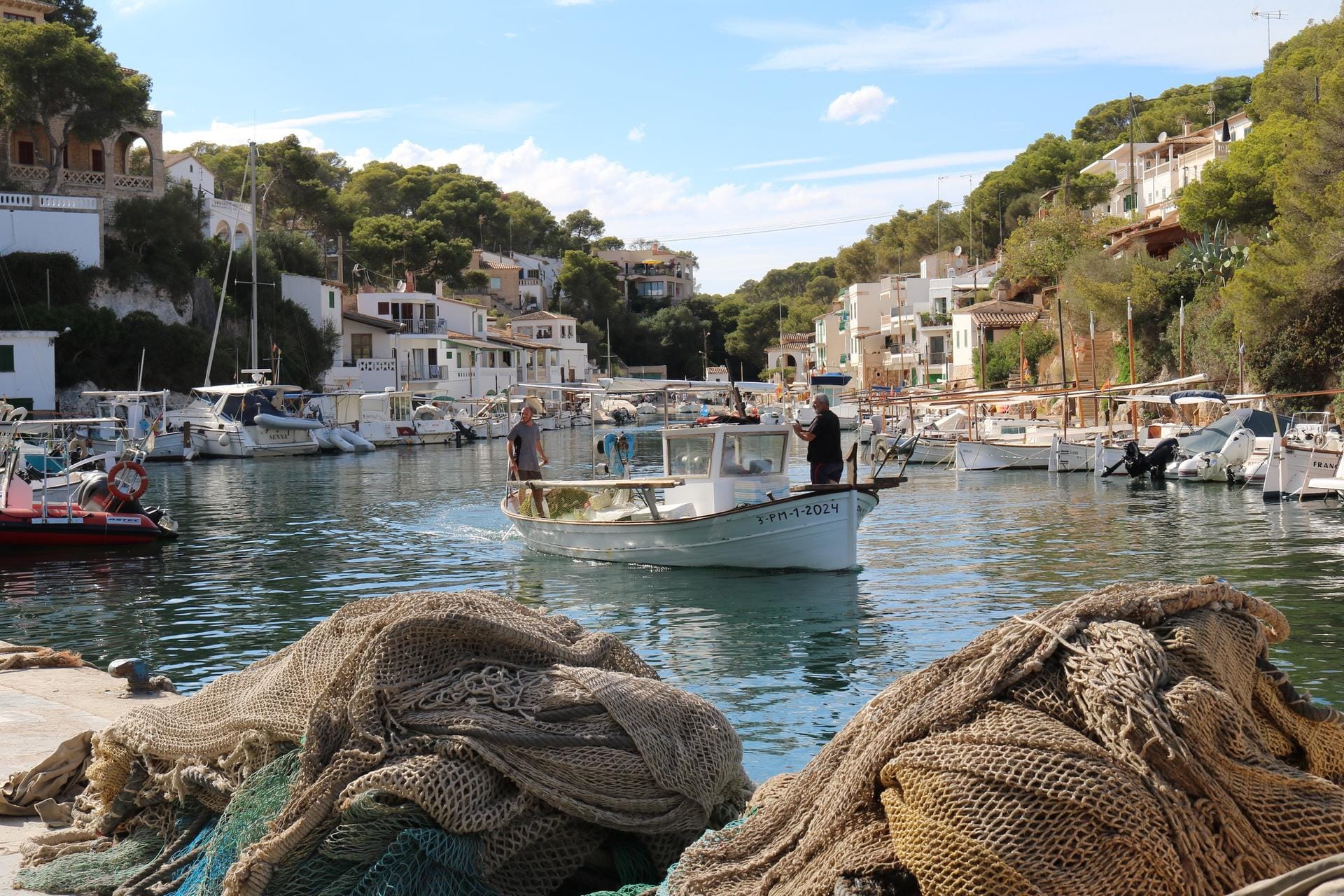 Fischerdorf Cala Figuera: Hier ist alles noch recht traditionell, Fischer nähen ihre Netze und das Meer schimmert zwischen den hellen Häusern mit den grünen Bootsgaragen.