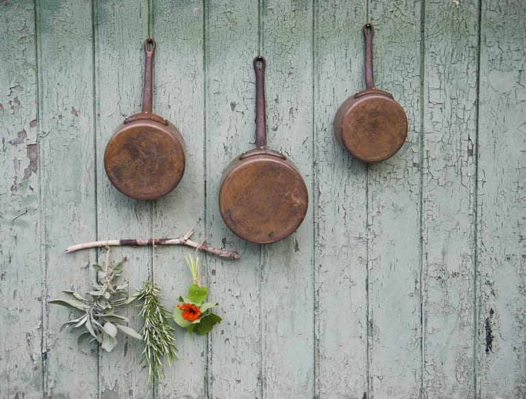Ausgediente Kupfertöpfe: Zum Bepflanzen sind sie nicht tief genug, deshalb am besten an eine Holzwand, zum Beispiel der Gartenlaube, hängen.