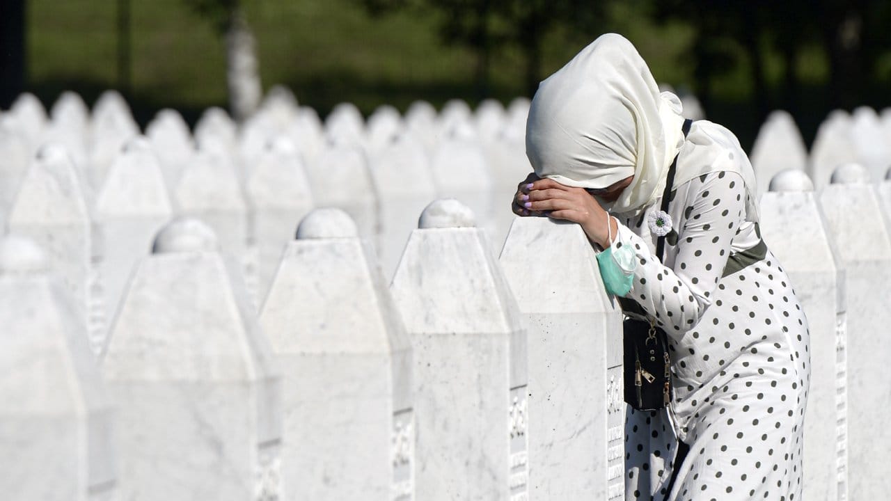 Eine Frau trauert auf dem Friedhof der Gedenkstätte Potocari in der Nähe von Srebrenica an einem Grab.