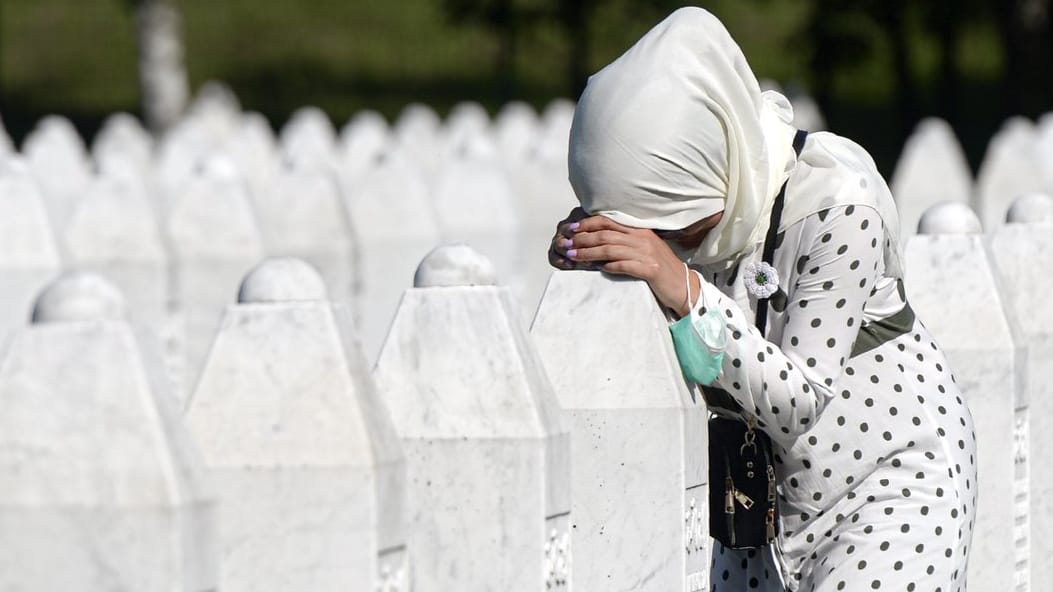 Eine Frau trauert auf dem Friedhof der Gedenkstätte Potocari in der Nähe von Srebrenica an einem Grab.