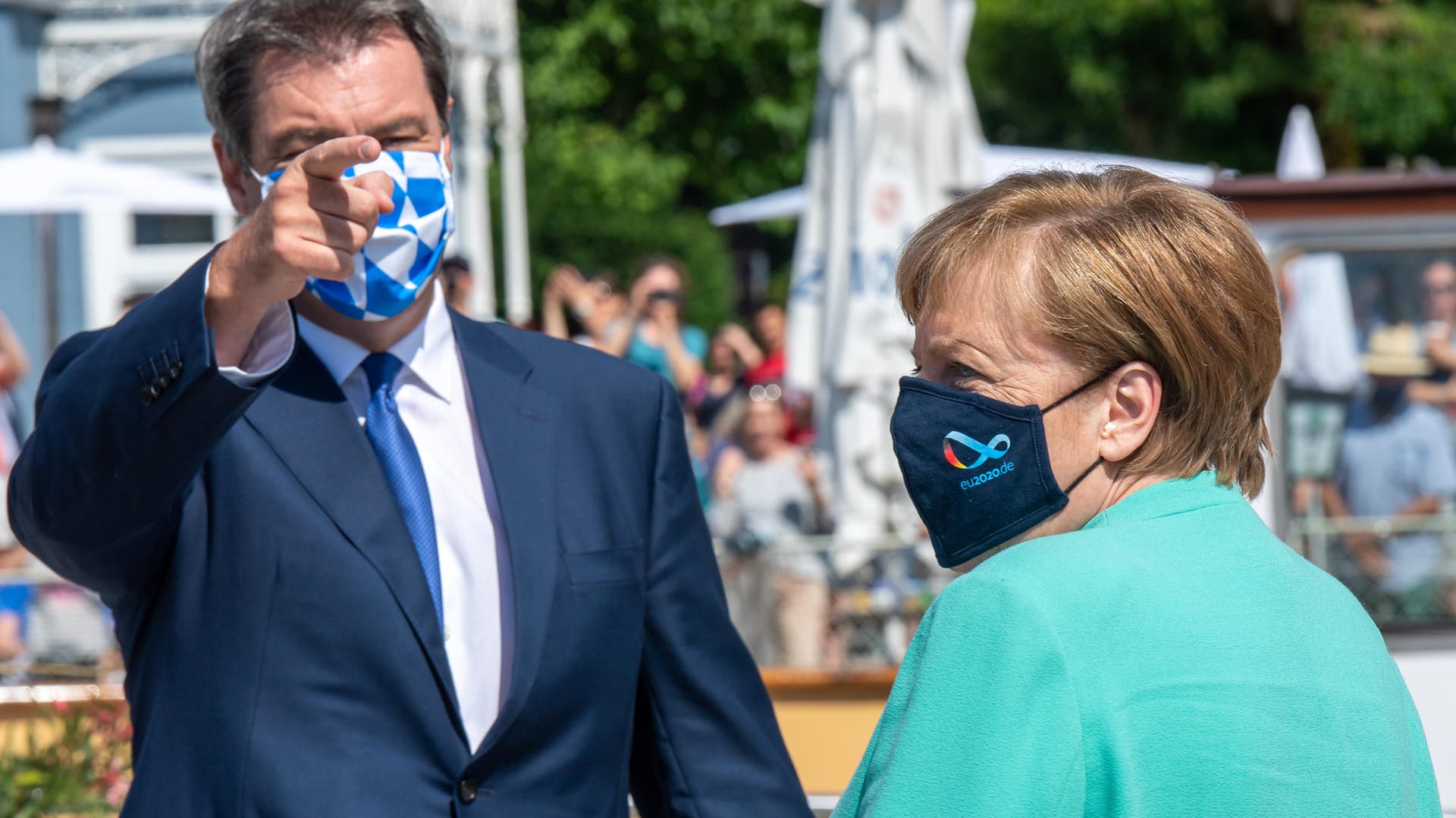 Willkommen in Bayern: Söder – mit weiß-blau-karrierter Maske – und Kanzlerin Merkel – ebenfalls mit Maske – an der Schiffsanlegestelle Prien vor der Überfahrt mit einem Schiff auf die Insel Herrenchiemsee.