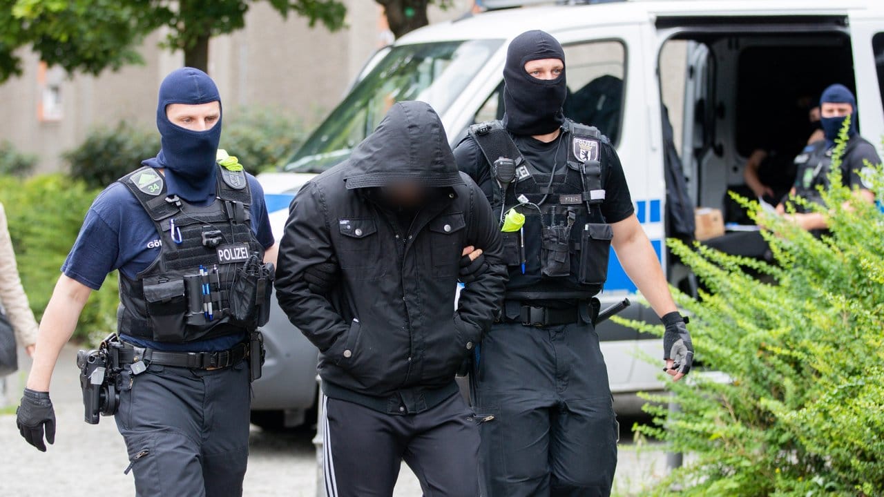 Ein Mann wird bei einem Polizeieinsatz im Rahmen einer groß angelegten Razzia gegen Tatverdächtige aus der islamistischen Szene in Berlin-Gesundbrunnen von zwei Polizisten abgeführt.
