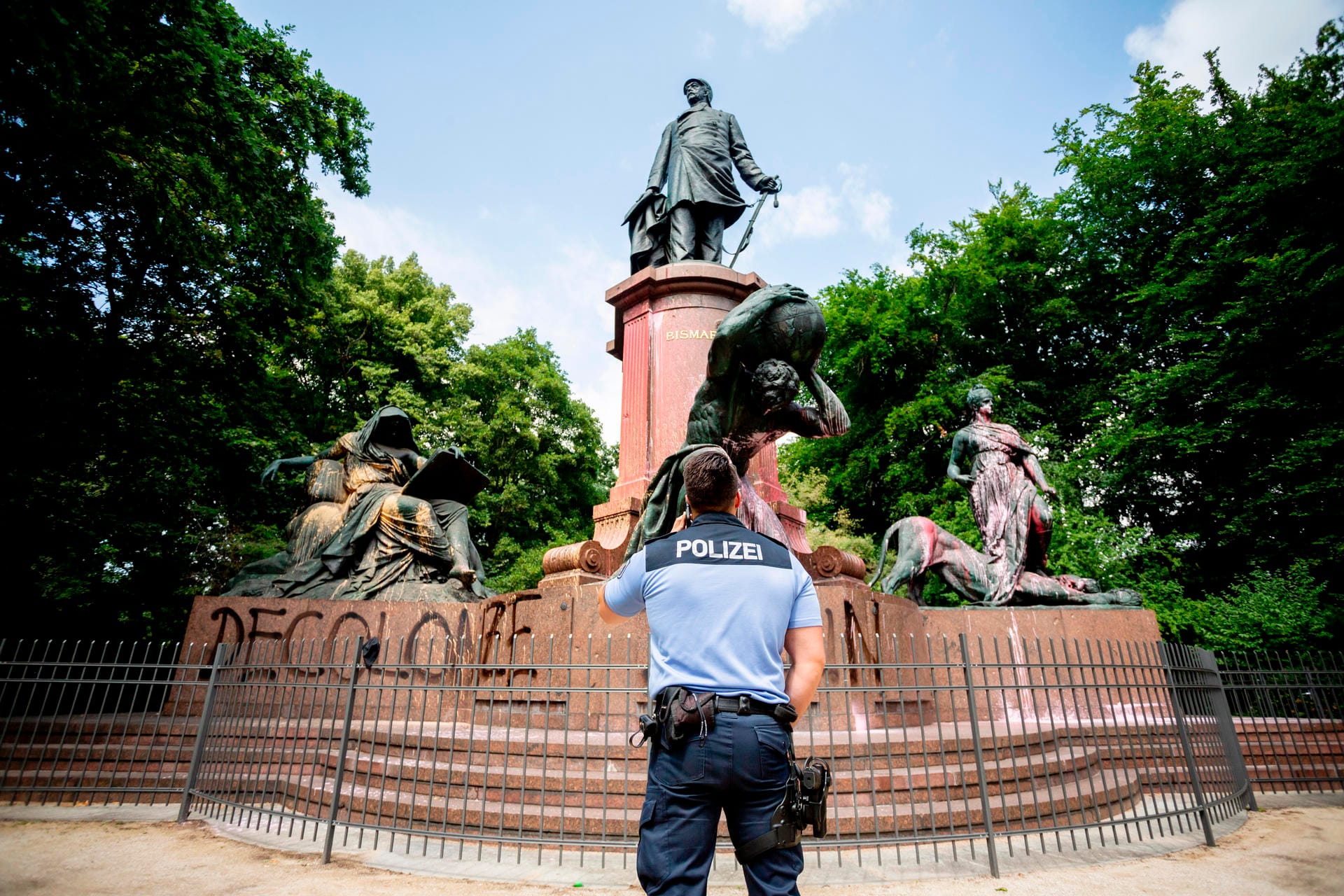 Farbattacke auf Bismarck in Berlin: Ein Polizist steht vor dem beschmierten Nationaldenkmal, auf das ebenfalls der Schriftzug "Decolonize Berlin" aufgesprüht wurde. Die Rolle Bismarcks in der Kolonialzeit ist umstritten.