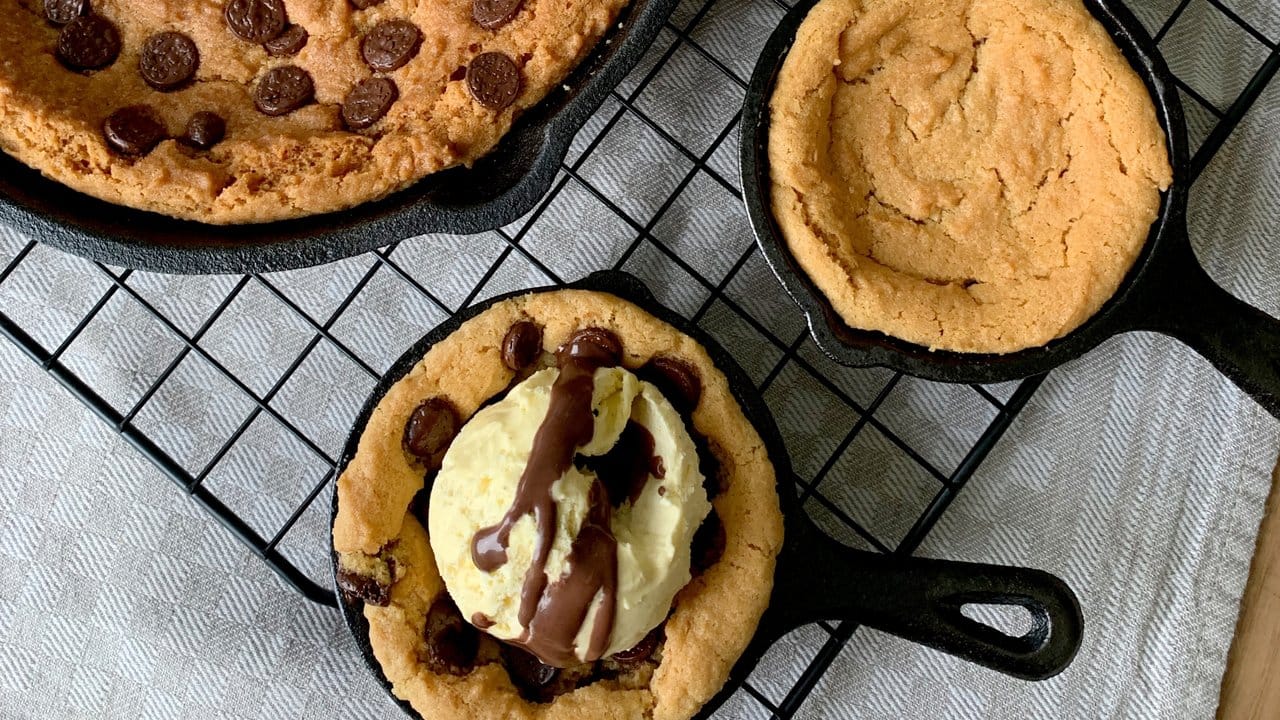 Ein großer Skillet Cookie mit Schokodrops in der Pfanne und zwei Mini Cookies - köstlich mit Vanilleeis.