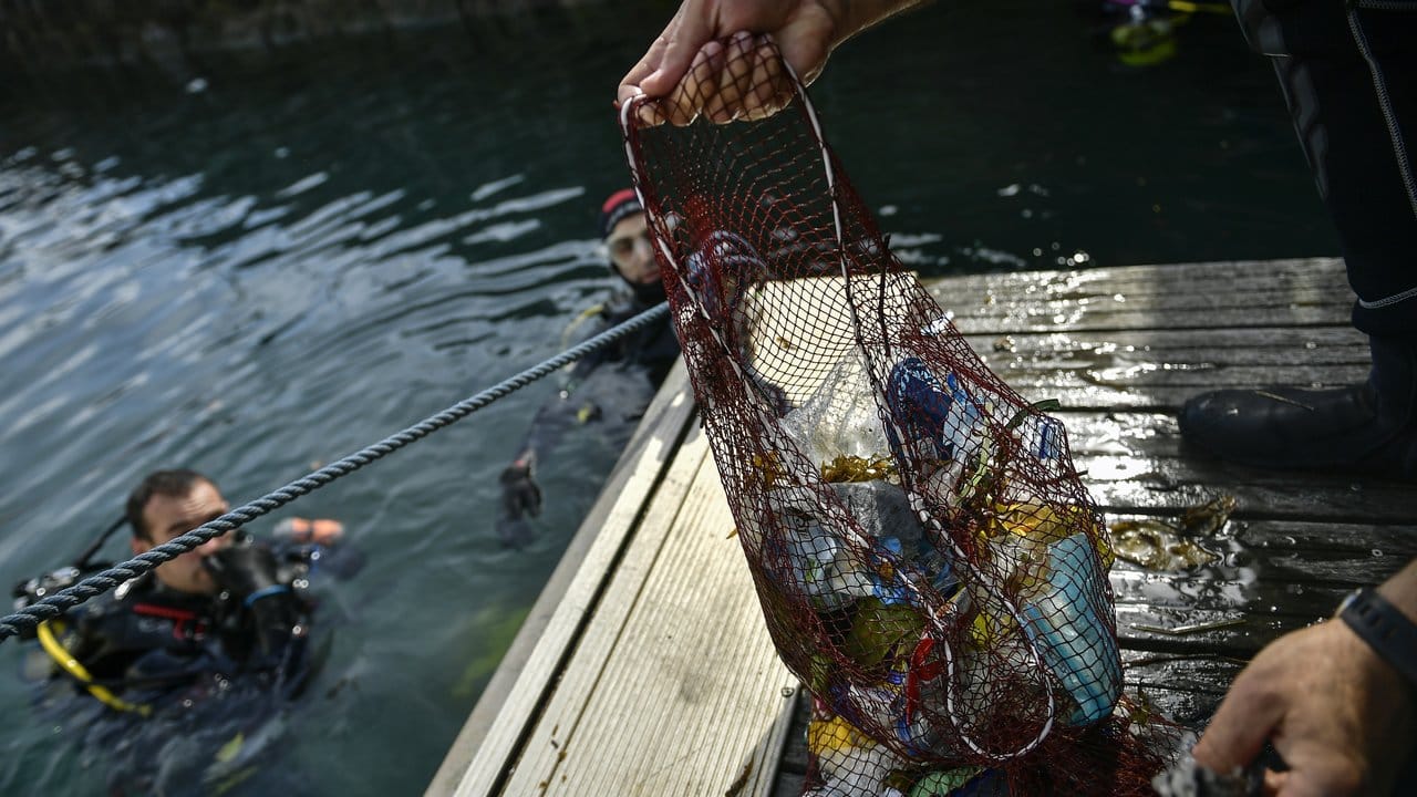 Ein Taucher hält ein Netz mit Abfällen, die er im baskischen Dorf Bermeo aus dem Meer entzogen hat.