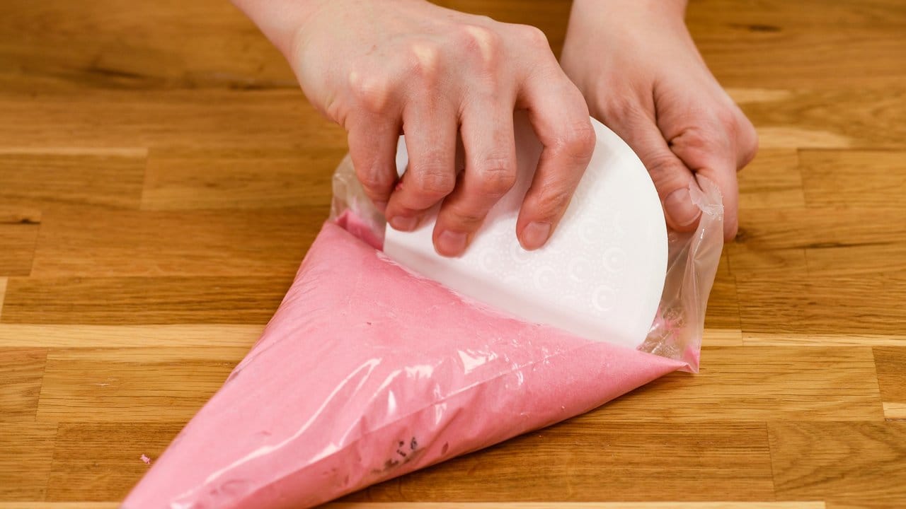 Nach dem Befüllen wird die Creme mit einer Teigkarte nach vorne Richtung Spritztülle geschoben. Nach dem Befüllen wird die Creme mit einer Teigkarte nach vorne Richtung Spritztülle geschoben.