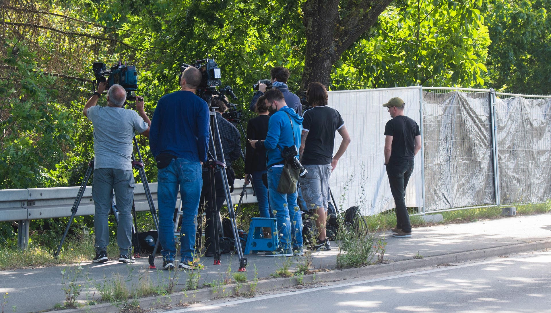Journalisten, Fotografen und Kamerateams stehen neben Sichtschutzzäunen bei dem Polizeieinsatz in der Kleingartenanlage.