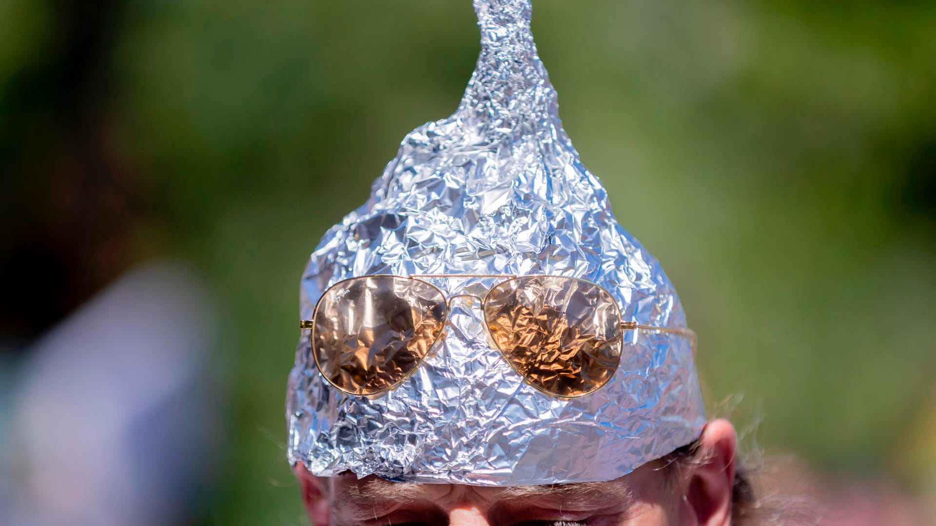 Ein Demonstrant trägt einen selbstgebastelten Aluhut. Verschwörungstheoretiker behaupten, mit diesen könne das angeblich von der Regierung betriebene Gedankenlesen verhindert werden.