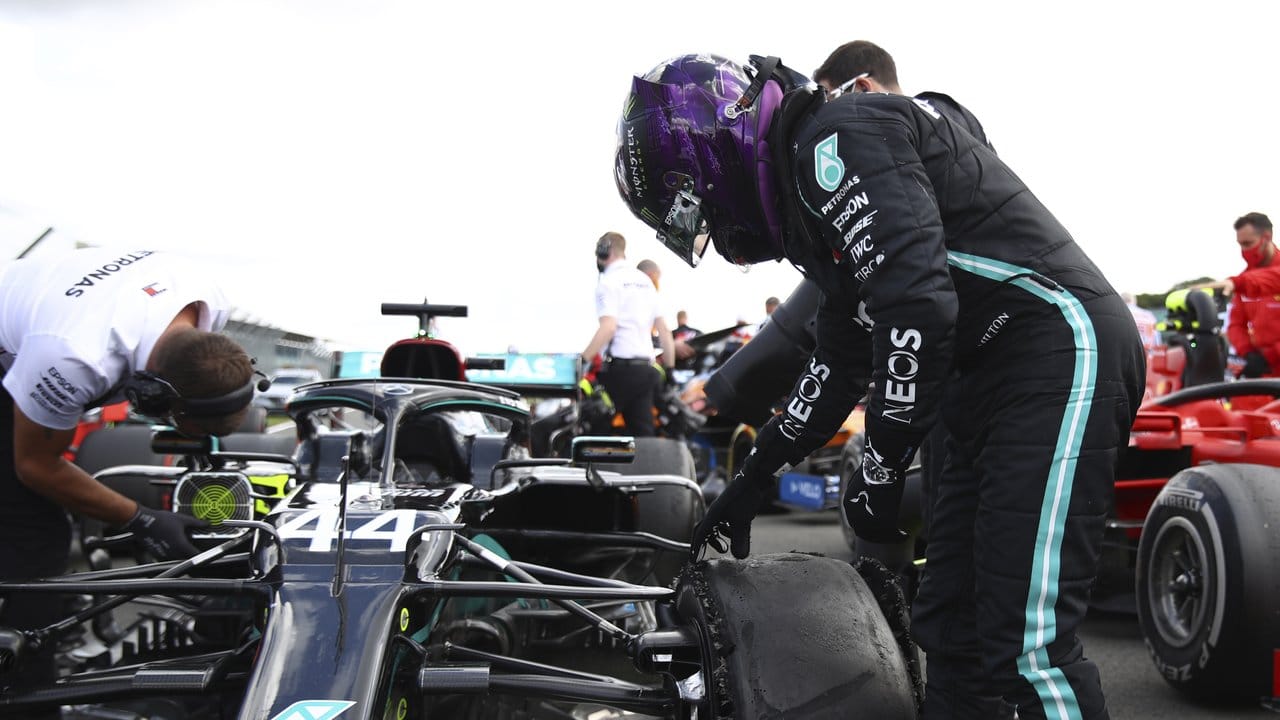 Hamilton schaut sich im Zielbereich den kaputten Reifen an.