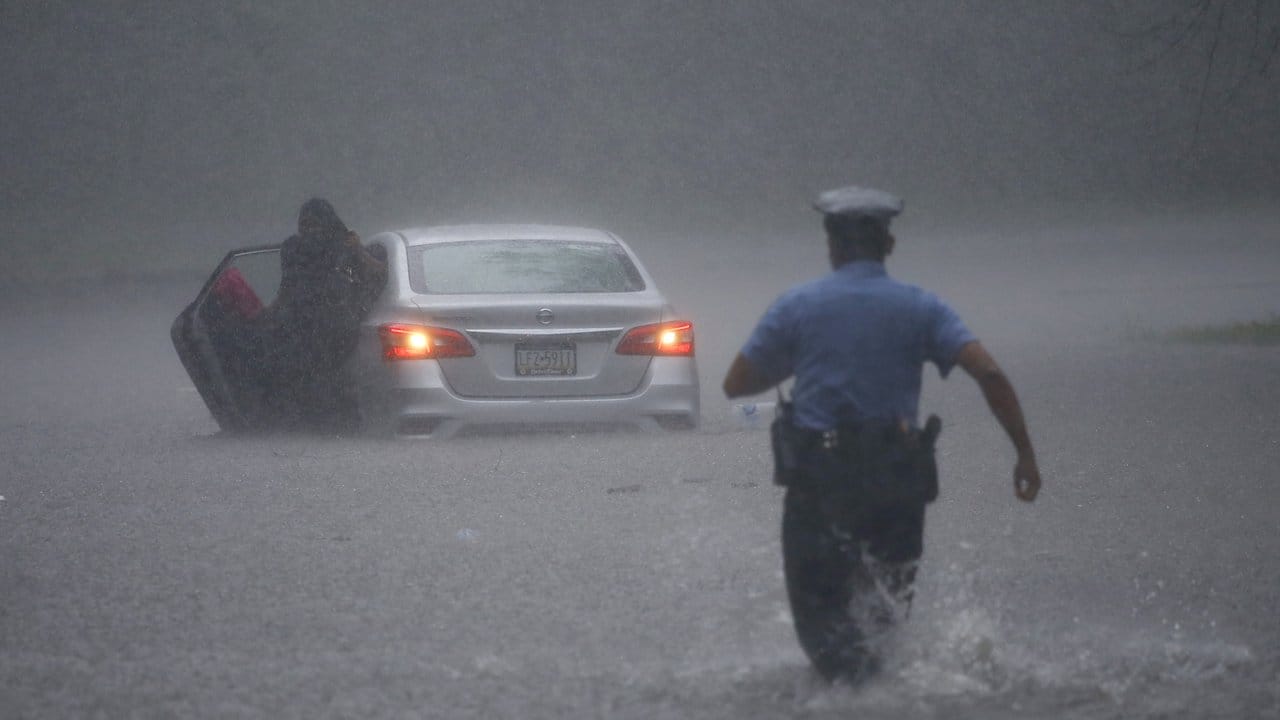 Ein Polizeibeamter eilt einem Autofahrer auf einer überschwemmten Straße in Philadelphia zu Hilfe.