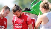 Fußballer in der Hessenliga in Zeilsheim: Die Sportler lassen sich mit der Gießkanne erfrischen.