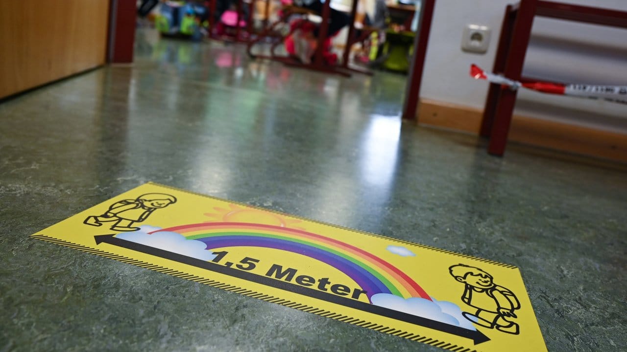 Ein Abstands-Hinweis klebt auf dem Fußboden einer Grundschule in Wiesbaden.