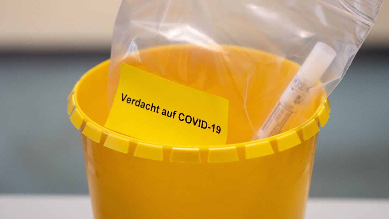 Ein Teströhrchen liegt in einer Tüte mit der Aufschrift "Verdacht auf COVID-19".