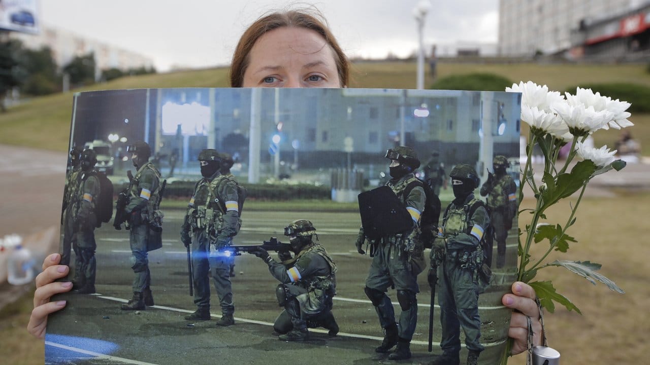 Bei einer Demonstration in Minsk präsentiert eine Frau ein Foto der gegen die Protestbewegung eingesetzten Sicherheitskräfte.