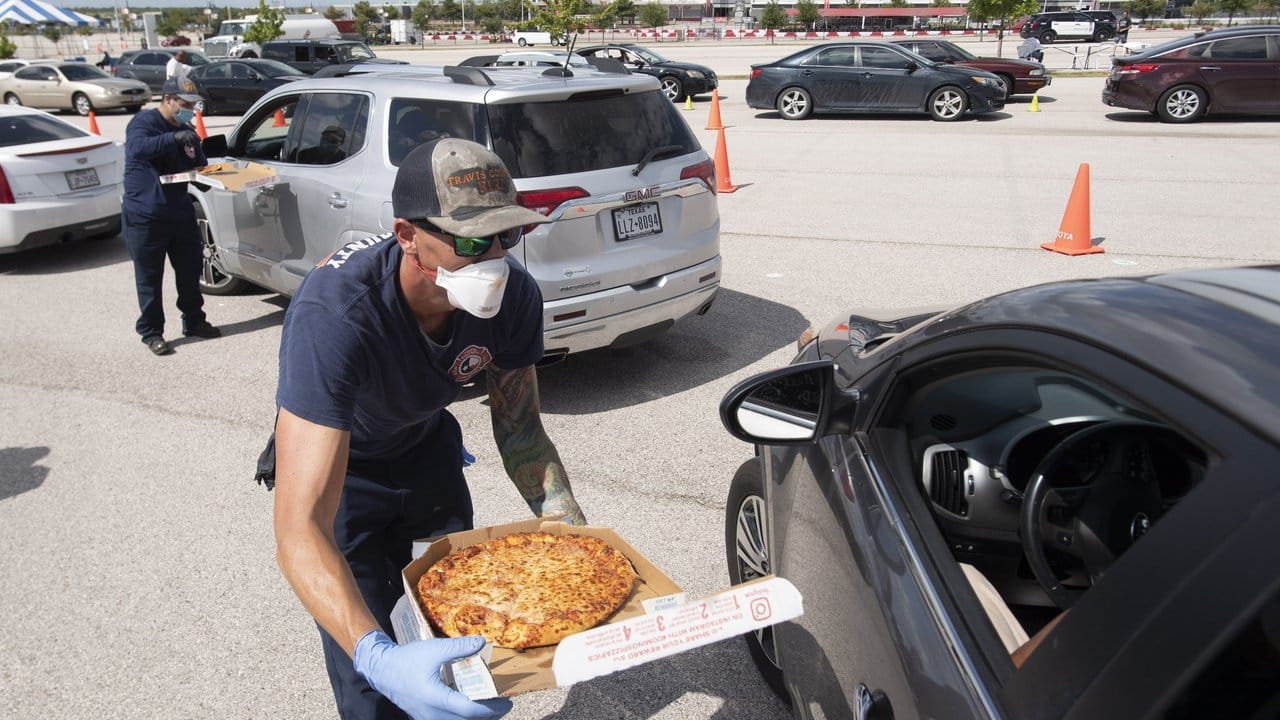 Feuerwehrleute reichen Autofahrern während der Evakuierung in Austin, Texas, Pizza.
