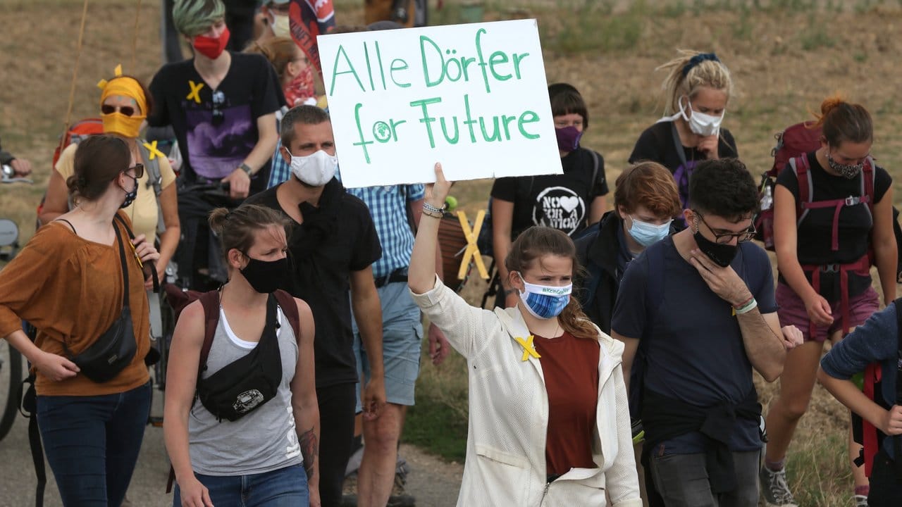 In dem Demonstrationszug aus Keyenberg zeigt Luisa Neubauer (M) ein Plakat mit der Aufschrift "Alle Dörfer for Future".