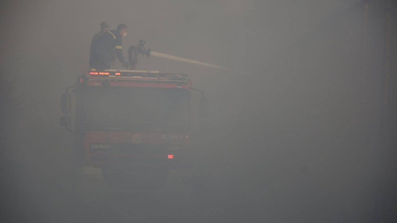 In dichten Rauch gehüllt versuchen Feuerwehrleute, die letzten Glutnester zu löschen.