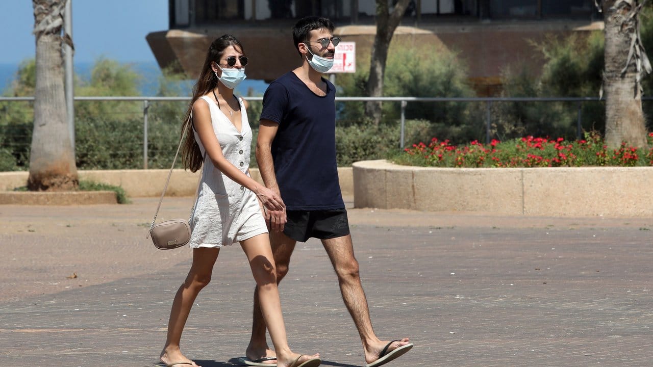 Passanten tragen Mundschutze, während sie auf einer Straße in Netanja gehen.