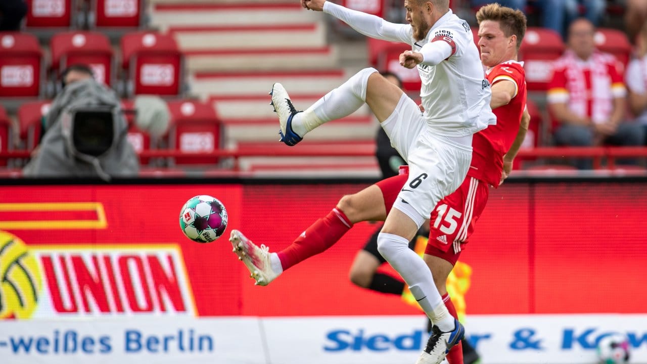 Jeffrey Gouweleeuw (l) vom FC Augsburg kämpft gegen Union-Spieler Marius Bülter um den Ball.